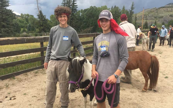 two students hold the lead rope of a mini horse during a service project with outward bound
